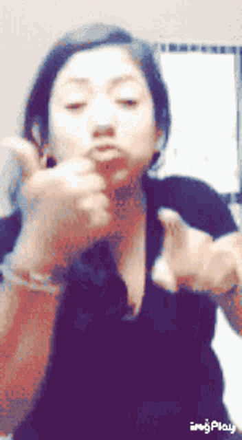 a woman in a black shirt is giving a thumbs up in a gif
