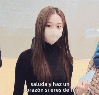 a woman wearing a face mask with the words saluda y haz un corazon si eres de riri below her