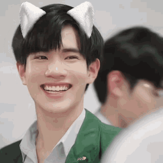 a young man wearing cat ears is smiling and looking at the camera .