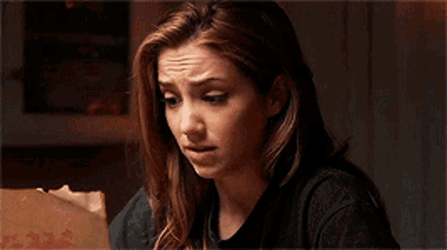 a woman in a black shirt is sitting in a dark room .