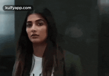 a woman with long hair and a white shirt is looking at the camera .