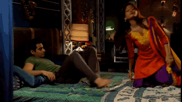 a man and a woman are laying on a bed with a lamp in the background