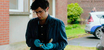 a man wearing blue gloves is standing in front of a white car