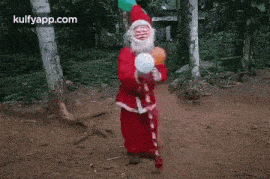 a santa claus doll is holding a candy cane and a balloon in a forest .