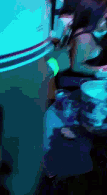 a blurred image of a person standing in a dark room with a blue light behind them