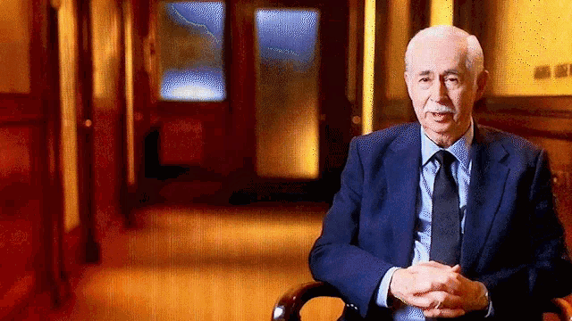 a man in a suit and tie sits in a chair