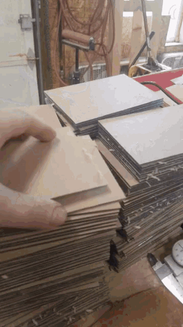 a person is holding a piece of cardboard next to a pile of cardboard