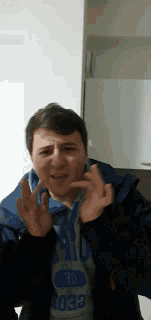 a man wearing a blue jacket and a grey shirt that says ' ao ' on it
