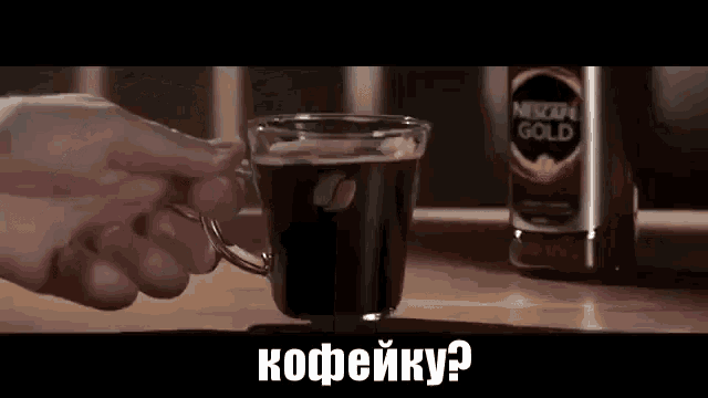 a person is holding a cup of nescafe gold coffee on a table .