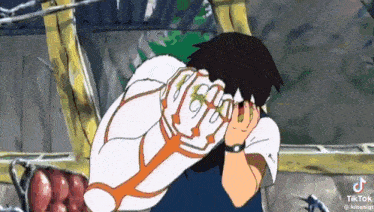 a cartoon character is covering his face with his hands while sitting down .