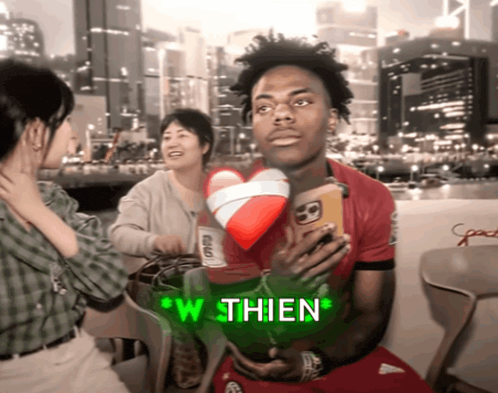 a man in a red shirt is holding a cell phone and says " w thien " on the screen
