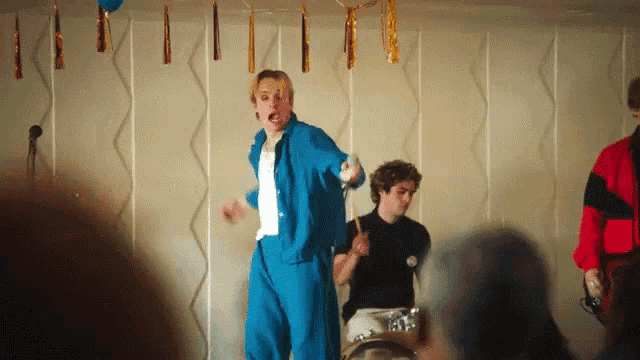 a man in blue pants is dancing in front of a microphone