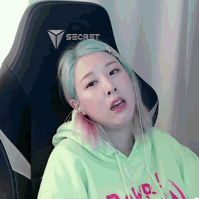 a girl wearing a green hoodie is sitting in a secret gaming chair