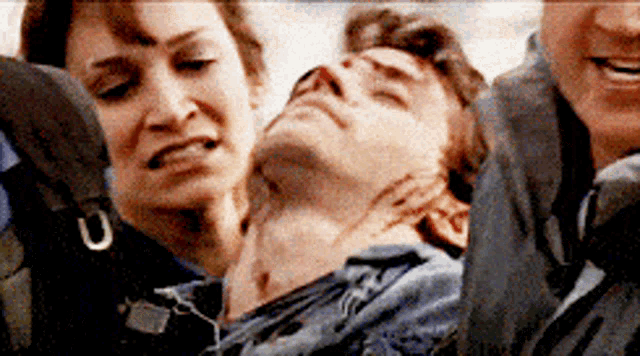 a woman is holding a man 's neck while a man looks on