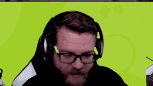 a man with a beard and glasses is wearing headphones and making a face .