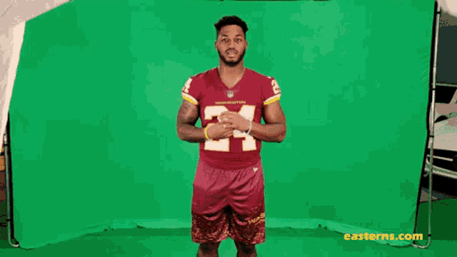 a man in a red jersey with the number 24 on it is standing in front of a green screen