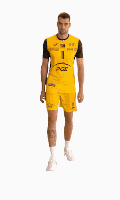 a man wearing a yellow shirt with the number 11 on it is standing with his arms crossed