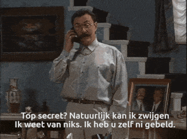 a man with glasses and a mustache is holding a cell phone and says " top secret "