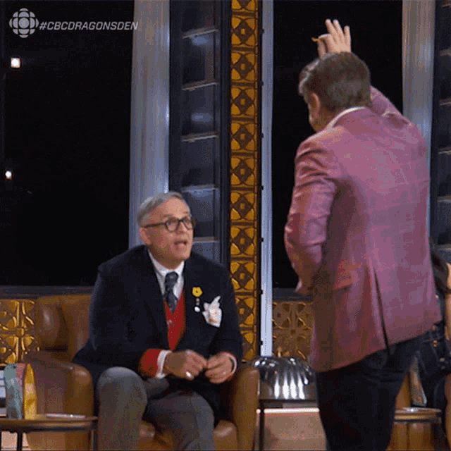 a man in a purple jacket is talking to another man
