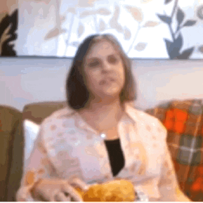 a woman sitting on a couch with a plate of chips in front of her