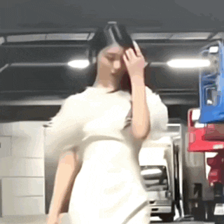a woman in a white dress is standing in a parking garage holding her hair .