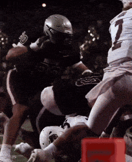 a football player with the number 1 on his jersey is tackled by another player