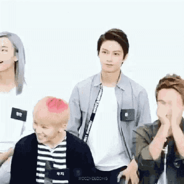 a group of young men are sitting next to each other and covering their faces .
