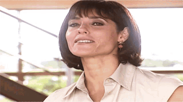 a woman wearing a white shirt and earrings smiles