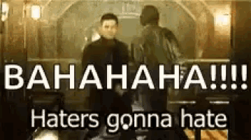 two men are standing next to each other in a room with the words `` haters gonna hate '' written on it .