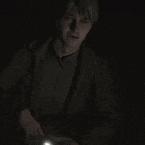 a man is holding a flashlight in a dark room .
