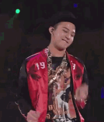a man wearing a red jacket and a hat is standing on a stage .