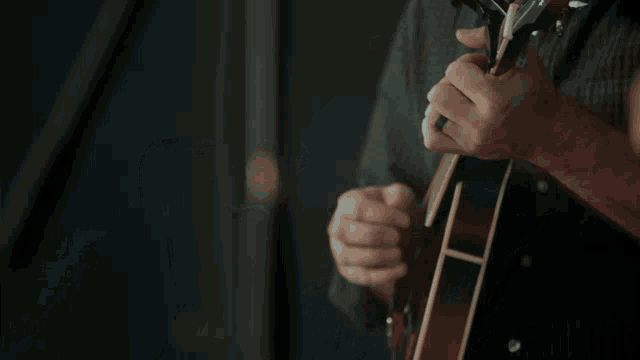 a man singing into a microphone with a guitar in the background
