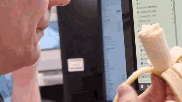 a man is peeling a banana in front of a computer screen that says standard components on it
