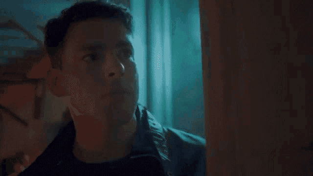 a man is looking out of a window and smoking a cigarette