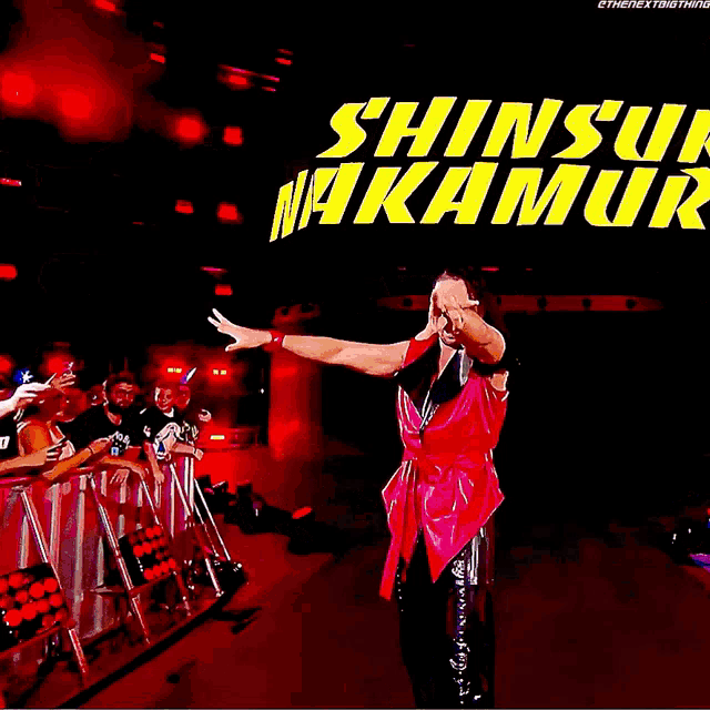 shinsuke nakamura is standing in front of a large screen that says shinsuke nakamura