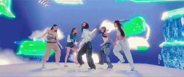 a group of young women are dancing on a stage in front of a green background .
