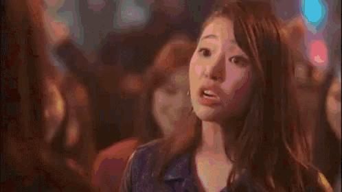 a woman with her eyes closed is standing in front of a crowd .