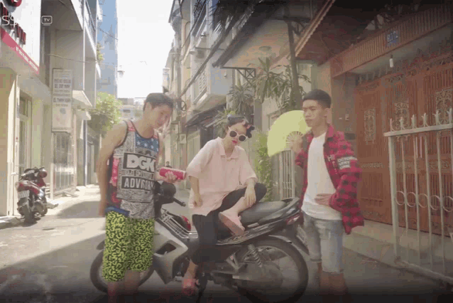 a man wearing a dgk shirt stands next to a woman on a scooter