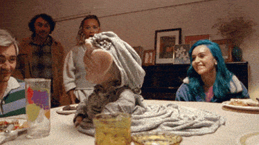 a woman with blue hair sits at a table with plates of food and a glass that says ' i love you ' on it