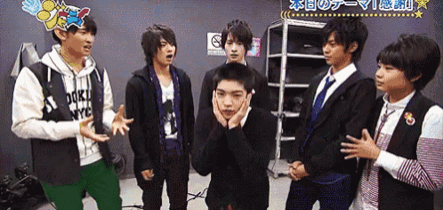 a group of young men are standing in a room with a no smoking sign behind them .
