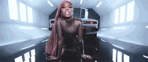 a woman with pink hair is kneeling in front of a car in a tunnel .