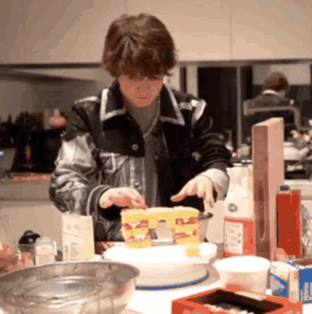 a man is preparing food in a kitchen with a box of powdered sugar on the table