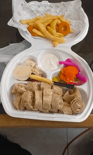 a styrofoam container filled with french fries and a chicken wrap