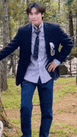 a man wearing a suit and tie is standing in a field .