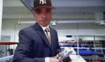 a man in a suit and tie is wearing a hat with the ny logo on it