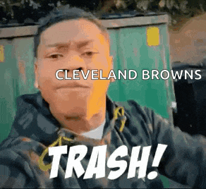 a man is taking a selfie in front of a dumpster with the words cleveland browns trash written on it .