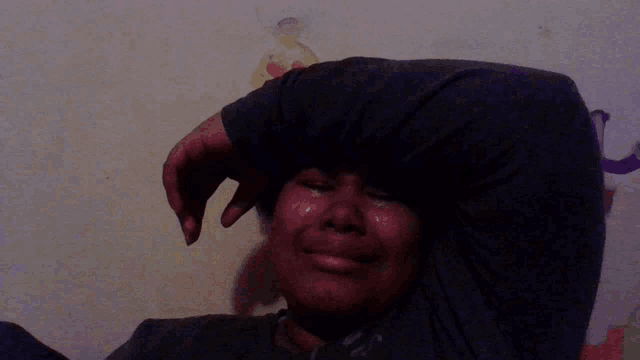 a woman with tears running down her face holds her hand to her forehead