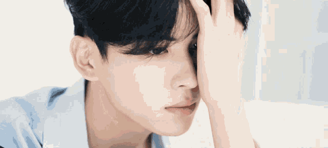 a close up of a young man covering his face with his hand