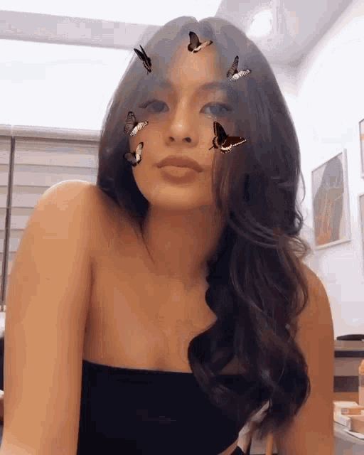 a woman with butterflies on her face is wearing a black strapless top