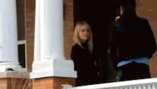 a man and a woman are standing on a porch .